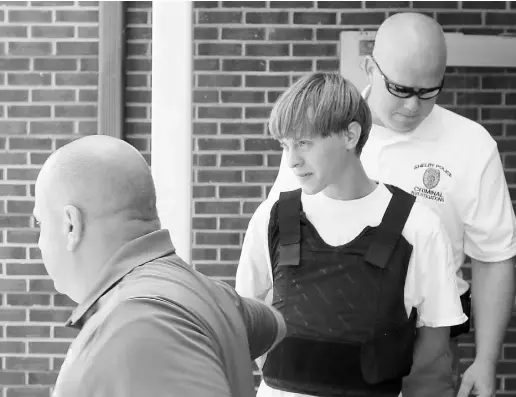  ?? Chuck Burton / the Associat ed Press ?? Charleston, S.C., suspect Dylann Storm Roof, centre, is escorted Thursday from the Shelby Police Department in Shelby,
N.C. Roof is a suspect in the shooting of nine people Wednesday night at the historic Emanuel church in Charleston.