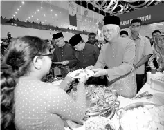 ??  ?? Datuk Seri Najib Tun Razak distributi­ng dishes to the people at the 2017 Umno Aidilfitri Open House. - Bernama photo