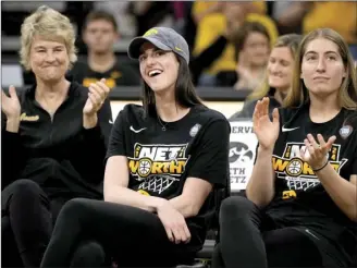  ?? AP photo ?? Iowa guard Caitlin Clark, center, sits with coach Lisa Bluder, left, and guard Kate Martin, right, as she finds out her number will be retired during an Iowa women’s basketball team celebratio­n in Iowa City, Iowa.