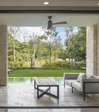  ??  ?? Above: The sheltered rear terrace overlooks a private garden and pool. Below: The open floor plan features a bespoke material palette and a gallery wall.