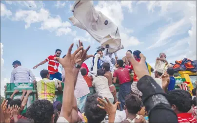  ?? AP PHOTO ?? Rohingya Muslim children, who recently crossed over from Myanmar into Bangladesh, reach out to catch clothes thrown toward them by locals near Balukhali refugee camp in Bangladesh.