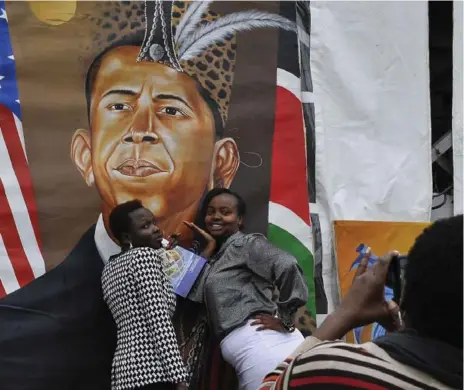  ?? TONY KARUMBA/AFP/GETTY IMAGES ?? Kenyan women pose for a photo in front of a painted artwork depicting U.S. President Barack Obama in Nairobi, on the eve of Obama’s visit to Kenya.