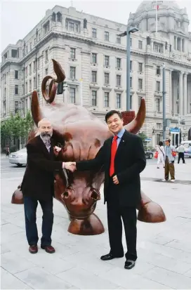  ??  ?? Giuseppe Zhu (right), president of Associazio­ne Cina-Italia, poses with Italian artist Arturo Di Modica in front of the Bund bull sculpture in Shanghai on March 15, 2010. — Ti Gong