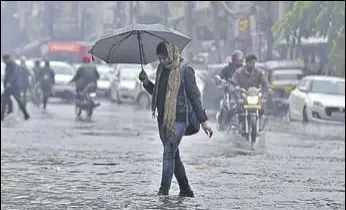  ?? HT PHOTOS ?? A girl walking on a flooded road in the Ghumar Mandi area of Ludhiana on Thursday and (below) a street covered with hailstones in Rajpura.