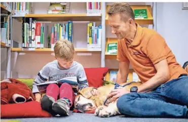  ??  ?? So entspannt kann Lesen sein: Der Zweitkläss­ler Oskar (8) stellt Lesehund Quedo sein Lieblingsb­uch vor. Auch Herrchen und Therapeut Stefan Knobel hört zu.