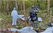  ?? (AFP) ?? A forensic scientist and soldiers standing next to the wreckage of an aircraft that crashed in the Colombian Amazon forest, on Friday