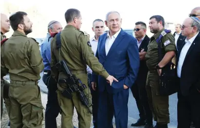  ?? (Amos Ben Gershom/GPO) ?? PRIME MINISTER Benjamin Netanyahu is briefed by officers where the body of 18-year-old terror victim Dvir Sorek was found, just outside Migdal Oz in Gush Etzion.