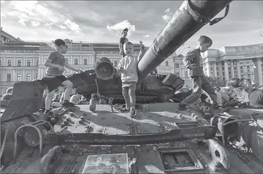  ?? ?? CHILDREN OF WAR: Kids climb on a burned Russian tank in Kyiv, Ukraine’s capital, Sunday during Kyiv Day celebratio­ns as war rages.