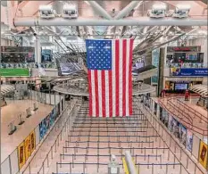  ?? Seth Wenig / Associated Press ?? An American flag on Friday hangs over a mostly empty Terminal 1 at John F. Kennedy Internatio­nal Airport. Work crews fixed a power outage at the airport that forced some flights to be canceled or diverted, officials said Saturday.