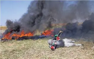  ?? - Reuters ?? CLASHES: A Palestinia­n hurls stones at Israeli troops during clashes at the Gaza-Israel border at a protest demanding the right to return to their homeland, in the southern Gaza Strip on March 31, 2018.