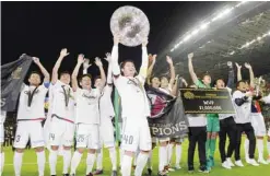  ??  ?? SAITAMA: Kashima Antlers’ Mitsuo Ogasawara (40) celebrates with trophies after beating Urawa Reds 2-1 in their second leg soccer match of the J-League Championsh­ip Final at Saitama Stadium in Saitama, near Tokyo, yesterday. Kashima claimed their eighth...