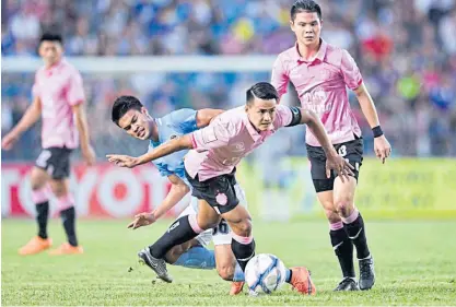  ??  ?? Buriram United captain Suchao Nutnum, centre, is tackled by a Pattaya United player.