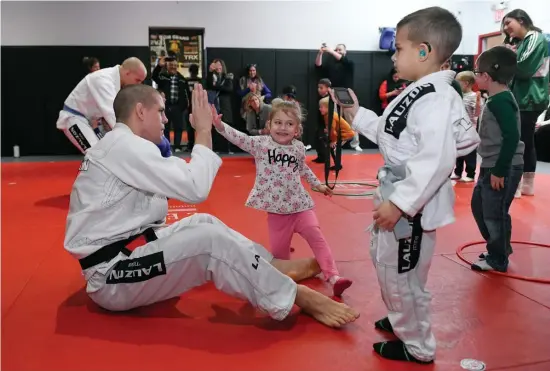  ?? FAITH NINIVAGGI PHOTOS / HERALD STAFF ?? WELCOME MAT: Joe Lauzon gets a high-five from Brigid Garden, 4, while his son Joey helps lead a class of hearing-impaired kids learning special exercises at Lauzon’s Easton studio. Fin Carr, below right, and Matthew DiVirgillo, below left, both 4, stretch during the class.