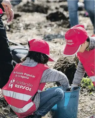  ??  ?? Voluntario­s medioambie­ntales ayudan a los niños a plantar árboles en Tarragona