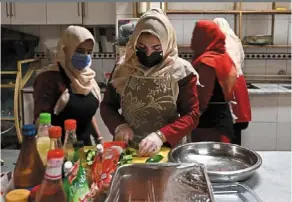  ??  ?? Women, who are survivors of domestic violence, cook at a restaurant establishe­d by akrami, who founded a shelter and a restaurant where women live and work, in Kabul.