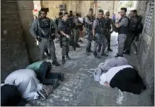  ?? ODED BALILTY — THE ASSOCIATED PRESS ?? Palestinia­ns pray as Israeli border police officers stand guard at the Lion’s Gate in Jerusalem’s Old City, Tuesday. Dozens of Muslims have prayed in the street outside a major Jerusalem shrine, heeding a call by clerics not to enter the site until a...