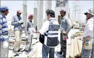  ?? Photos by Mohammad Morsi ?? Ministry inspector issues citation to the workers for flouting the ban to work under direct sun between 11:00 am to 4:00 pm.