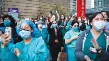  ?? AP FILE PHOTO/JOHN MINCHILLO ?? Medical personnel attend a daily 7 p.m. applause in their honor, during the coronaviru­s pandemic outside NYU Langone Medical Center in the Manhattan borough of New York.