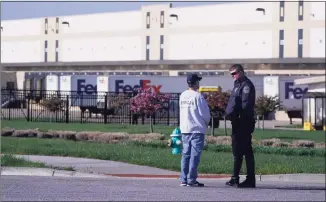  ?? Michael Conroy / Associated Press ?? A police officer stands near the scene where multiple people were shot at the FedEx Ground facility early Friday morning in Indianapol­is.