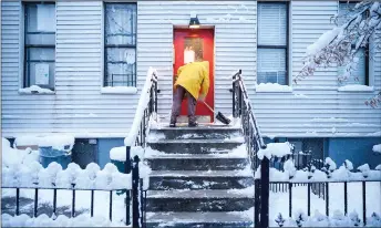  ?? — AFP photo ?? A man shovels snow from a doorway on a street in Brooklyn borough of New York during the first snow storm of the season.