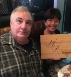  ?? PEG DEGRASSA - DIGITAL FIRST MEDIA ?? Mike and Bernadette Colantonio of Havertown hold up the autographe­d wooden cutting board that they received as a gift at the Guy Fieri’s Philly Restaurant &amp; Bar Wednesday night. The couple sampled the restaurant’s signature dishes and met Guy Fieri in-person.