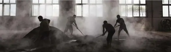  ??  ?? Chinese workers spread steamed sorghum on the ground as they prepare it for the first fermentati­on to be used in locally made baijiu at the Maopu Health Liquor Co. Distillery in Maotai.