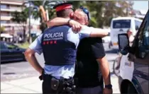  ?? ALEX CAPARROS, GETTY IMAGES ?? A man hugs a police officer on the spot where five suspected terrorists were shot by police in Cambrils, Spain, on Friday. Fourteen people were killed when a van hit crowds in the tourist area in Barcelona on Thursday.