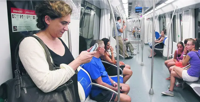  ??  ?? Unas jóvenes observan a la alcaldesa de Barcelona durante un trayecto en metro