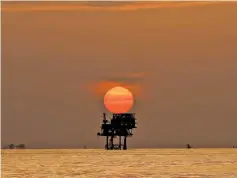  ??  ?? An offshore oil platform and wells are silhouette­d by the setting sun in the Gulf of Mexico off the Louisiana coast on July 15, 2010.