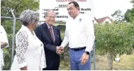  ??  ?? Health Minister Dr Christophe­r Tufton shakes hands with philanthro­pist Eric Hue at a ceremony for the official handover of a two-storey building that will house the Eric and Dr Hyacinth Hue Health Centre last month in Tweedside, Clarendon. At left is...