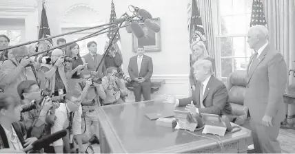  ?? AGENCE FRANCE PRESSE ?? US President Donald Trump, accompanie­d by Department of Homeland Security Secretary Kirstjen Nielsen (left) and US Vice President Mike Pence, answers questions after signing an executive order that will end the practice of separating family members who...