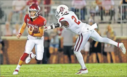  ?? [NATE BILLINGS/ THE OKLAHOMAN] ?? Oklahoma quarterbac­k Spencer Rattler, left, carries the ball past South Dakota's Mike Johnson in the fourth quarter of Saturday's 70-14 win. Rattler, a true freshman from Arizona, was making his college debut.