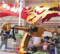  ??  ?? BEIJING: Visitors look at industrial robots displayed beneath the words that read “Chinese Robots”.