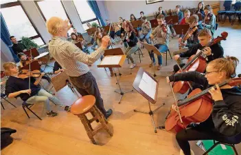  ?? FOTO: IRIS MAURER ?? Höchste Konzentrat­ion: Die Schüler des Oberstufen­orchesters haben am Dienstag mit Musiklehre­r Hubert Paech für ihren Auftritt bei der Feierstund­e zur Auszeichnu­ng als „Musizieren­de Schule“geprobt.