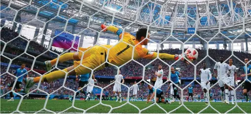  ??  ?? France goalkeeper Hugo Lloris is at full stretch to deny Uruguay’s Martin Caceres in last night’s quarter-final while, below, Uruguay’s Fernando Muslera fumbles the ball into his own net