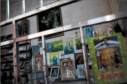  ?? AP/ANDY WONG ?? Catholic religious paintings and Bibles are displayed behind bars at an undergroun­d Catholic church in Jiexi county in south China’s Guangdong province. A group that monitors Christiani­ty in China says the government is increasing its crackdown on congregati­ons in Beijing and several Chinese provinces, destroying crosses, burning Bibles and ordering followers to sign papers renouncing their faith.