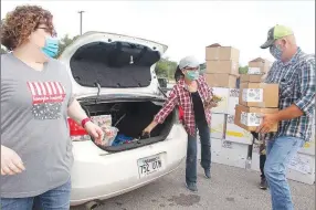  ?? LYNN KUTTER ENTERPRSE-LEADER ?? Melissa Payne, left, of Farmington, Brad Ping, right, of Prairie Grove, and another volunteer place food in a vehicle during the Tyson Foods’ Food Giveaway on Saturday at Lincoln High School parking lot.