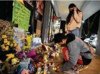  ?? Jeenah Moon / New York Times ?? Jeffrey Riso and Cindy Callejas add candles to a makeshift memorial outside Young’s Asian Massage in Acworth, Ga., in honor of the victims of the deadly Atlanta-area shootings.