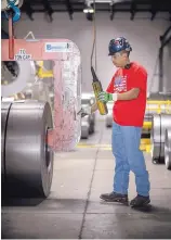  ??  ?? Stanco Metal Products worker Joe Martinez loads steel that will be used to make industrial parts.