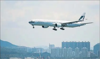  ?? XAUME OLLEROS / BLOOMBERG ?? Un avión de Cathay Pacific sobrevuela los suburbios de Hong Kong antes de aterrizar