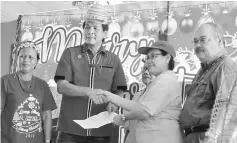  ??  ?? Dennis (second left) presents a grant to Long Ikang village chief Catherina Madang.