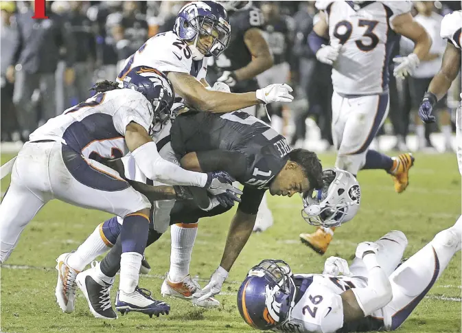  ?? — AP ?? OAKLAND: Oakland Raiders wide receiver Michael Crabtree (15) loses his helmet while tackled by Denver Broncos cornerback Bradley Roby, left, cornerback Chris Harris (25) and free safety Darian Stewart (26) during the second half of an NFL football game...