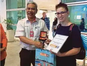  ??  ?? Malaysia Airports (Sepang) Sdn Bhd acting general manager Arif Jaafar presenting a commemorat­ive klia2 medallion to Australian Natalie Parish at the Kuala Lumpur Internatio­nal Airport 2 in Sepang yesterday.