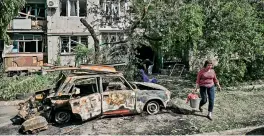  ?? — AFP ?? A woman walks next to a burnt car in front of a damaged appartment building after a strike in the city of Slovyansk at the eastern Ukrainian region of Donbas on Tuesday, amid Russia’s invasion of Ukraine.