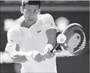  ?? OLI SCARFF/GETTY IMAGES ?? Novak Djokovic returns a shot in his straight-set victory over Ernests Gulbis on Saturday at the All England Club.