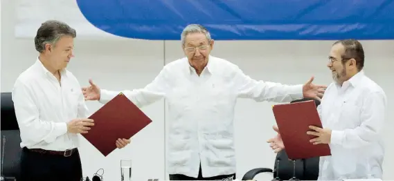  ??  ?? El presidente de Colombia, Juan Manuel Santos (izquierda), y el comandante de las FARC, Timoleón Jiménez (derecha), firmaron un acuerdo de cese al fuego y de desarmamie­nto el 23 de junio de este año en La Habana en presencia del líder cubano, Raúl...