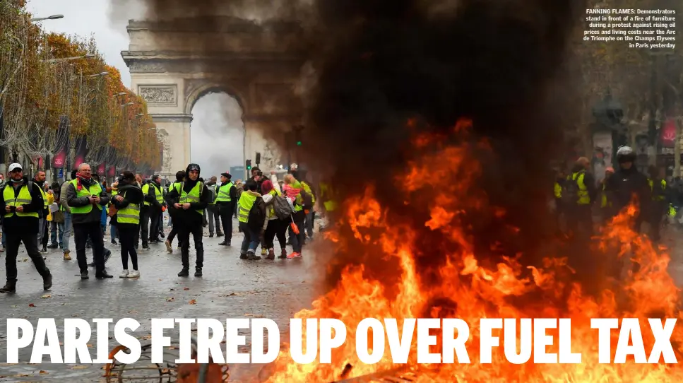  ??  ?? FANNING FLAMES: Demonstrat­ors stand in front of a fire of furniture during a protest against rising oil prices and living costs near the Arc de Triomphe on the Champs Elysees in Paris yesterday