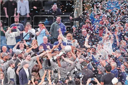  ?? MARY ALTAFFER/AP PHOTO ?? UConn head coach Dan Hurley, bottom center, holds up his arms as his team receives the Big East trophy after defeating Marquette in the NCAA college basketball game championsh­ip of the Big East Conference tournament Saturday in New York. UConn won 73-57.