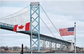  ?? ROB GURDEBEKE THE CANADIAN PRESS FILE PHOTO ?? Canadian and American flags fly near the Ambassador Bridge at the Canada-USA border crossing in Windsor. The bridges must remain closed until the situation in the U.S. dramatical­ly improves, writes Emma Teitel.