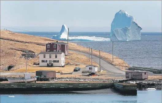  ?? PAUL DALY/CP ?? A large iceberg is visible from the shore in Ferryland. After turning heads for locals, visitors and the internatio­nal media, the massive berg is on the move.
